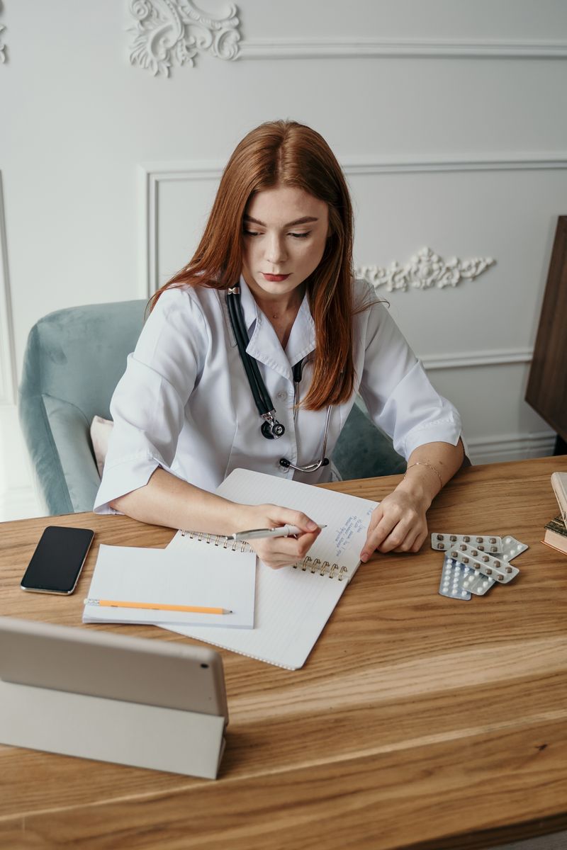 A clinician writing visit notes beside a stethoscope
